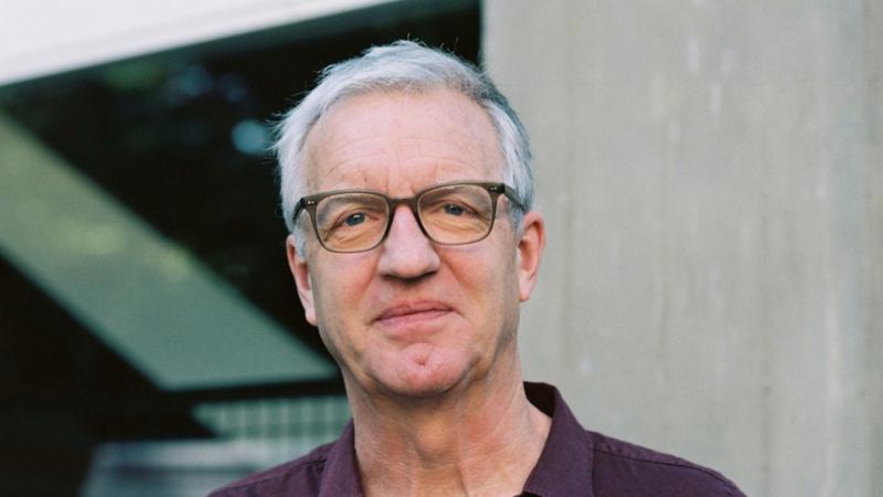 Person wearing glasses looking at camera and wearing a purple shirt.