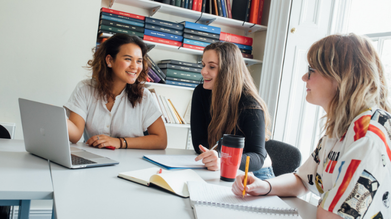 three female students sitting together with laptops