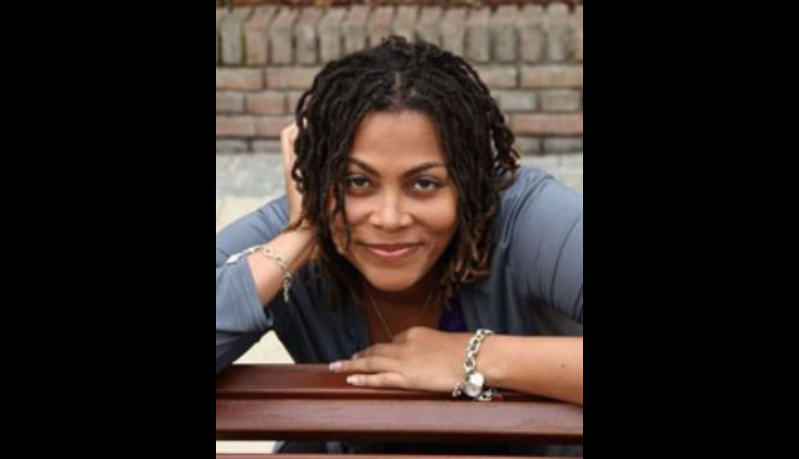 head and shoulders of woman resting her head on her hand and smiling into camera