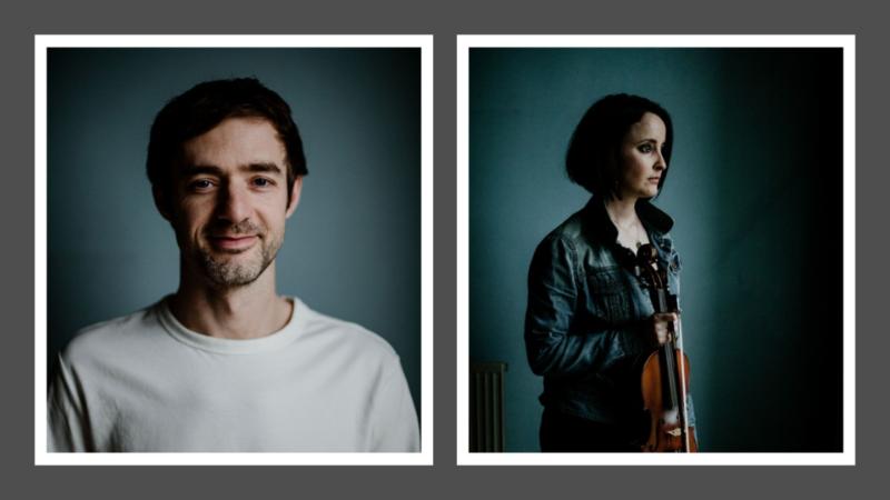 A person looking directly at the camera and a person looking to the side holding a fiddle.