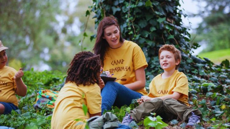 students working in a summer camp chatting to children