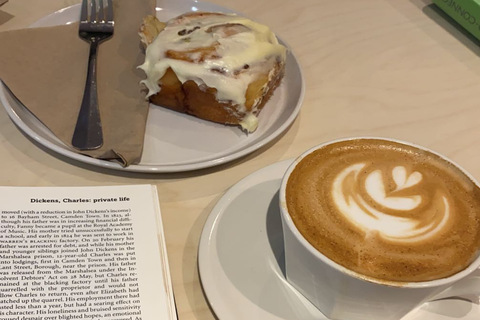 Cup of coffee and traybake beside Dickens book