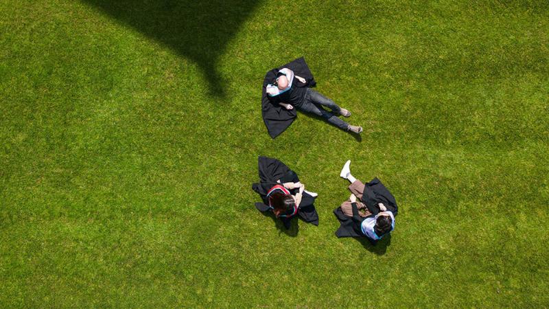 Three students on grass in the Quad