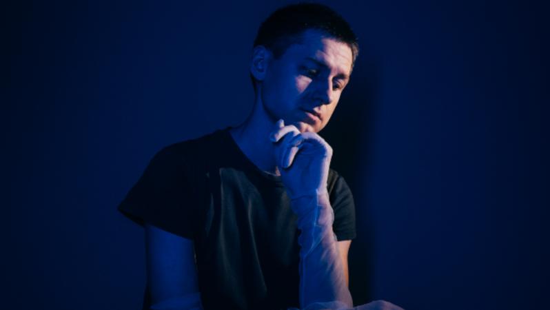 Person sitting with holding chin in hand whilst wearing a clear glove