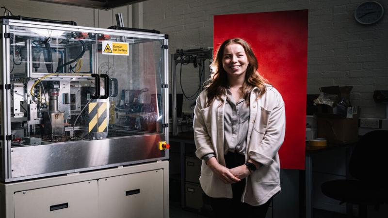 Research student standing beside machine