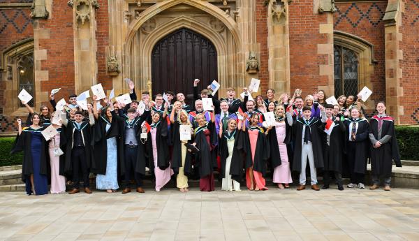 01. R-City graduates celebrate outside Queen’s iconic Lanyon Building, proudly raising their certificates in a moment of joy and achievement.