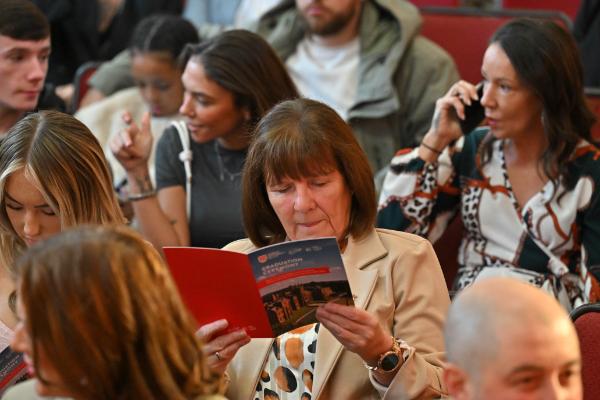 09. Audience members take in the programme details, reflecting on the collaboration and learning that shaped each graduate’s experience.