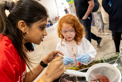 A female PhD student shows a child in a lab coat how to extract DNA from strawberries at the Balmoral Show 2024