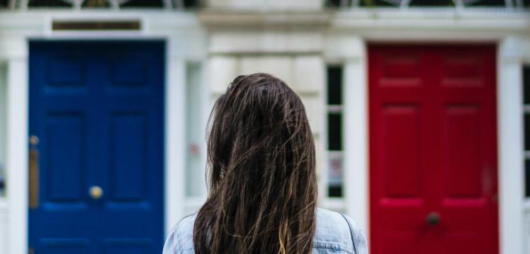 Person choosing between a red door and a blue door