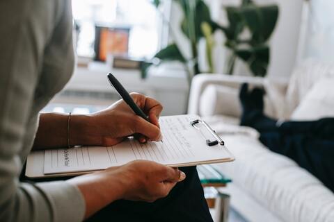 Doctor taking notes while patient lies on bed