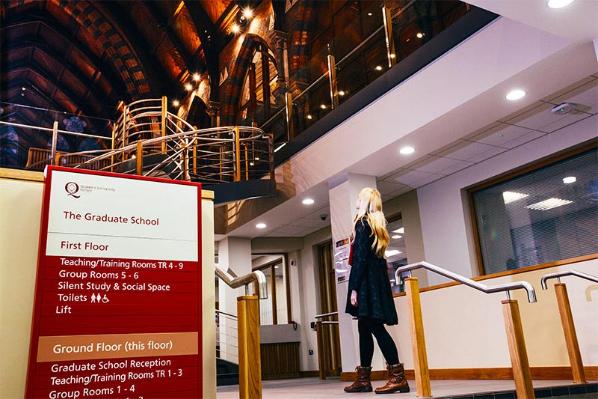 student in graduate school entrance foyer, looking up to first floor