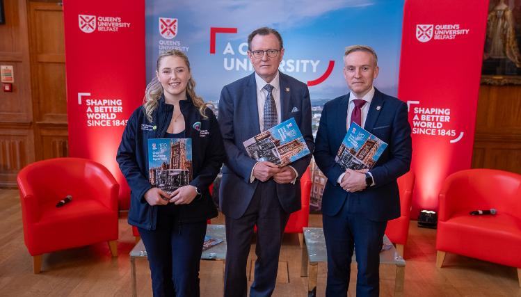Three people stand with a Civic University Agreement document looking at the camera