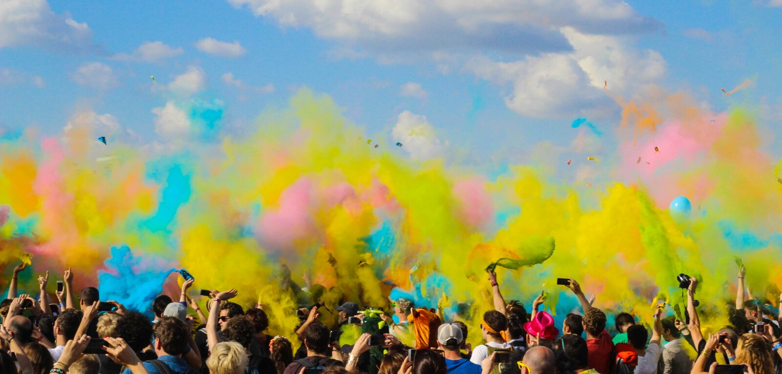 Large group of people celebrate as mists of colour hover above them