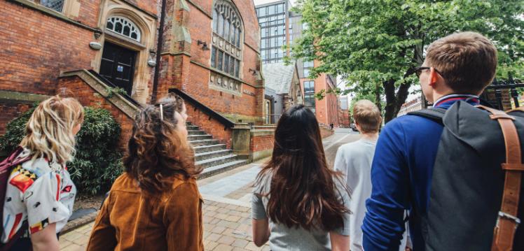 Five students walking past the QUB music building