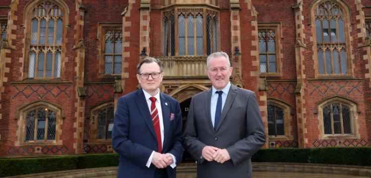 Two men standing outside a university looking at the camera