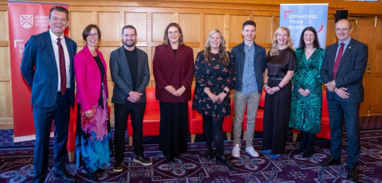 A group of people, including author Katriona O'Sullivan, stand posed in a university grand hall, looking towards the camera.