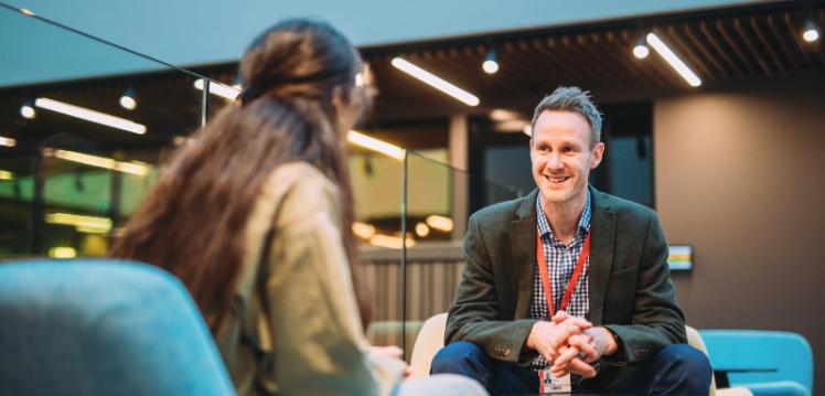 Male QUB staff member talking to female student inside the One Elmwood Student Centre