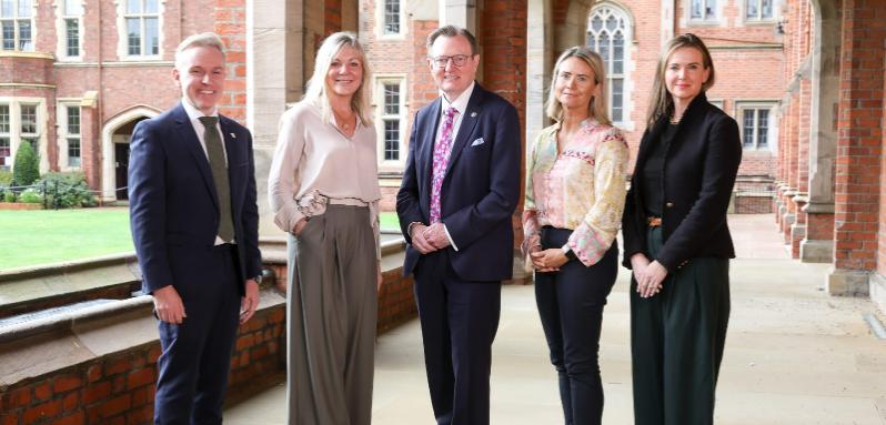 A group of people from NI Chamber and Queen's University stand posed on the University quad looking at the camera