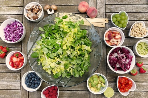 Bowls of salad and vegetables on top of table