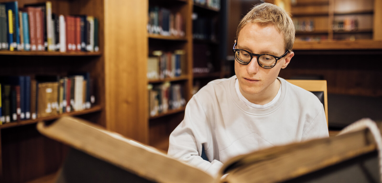 Student reading large book in McClay Library