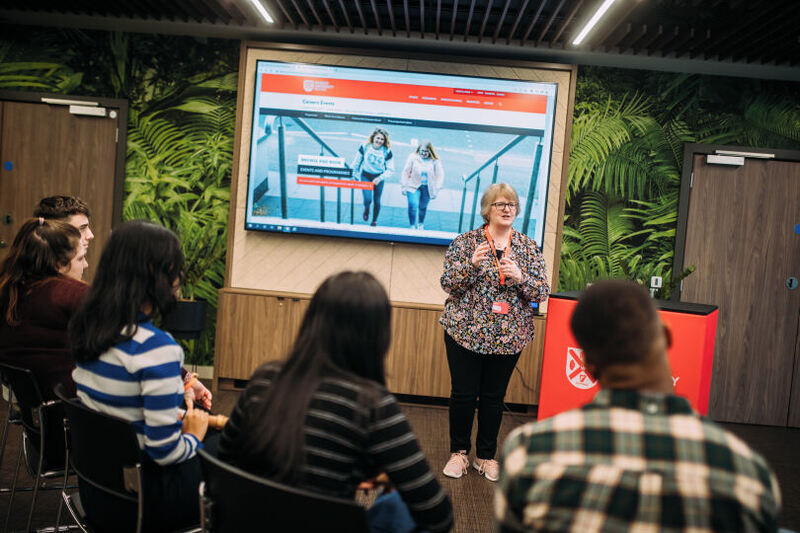 Staff speaking at information session in front of students