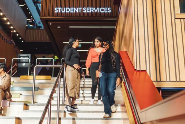 Three students walk downstairs in the SU