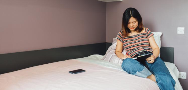 Student studying on top of bed in accommodation