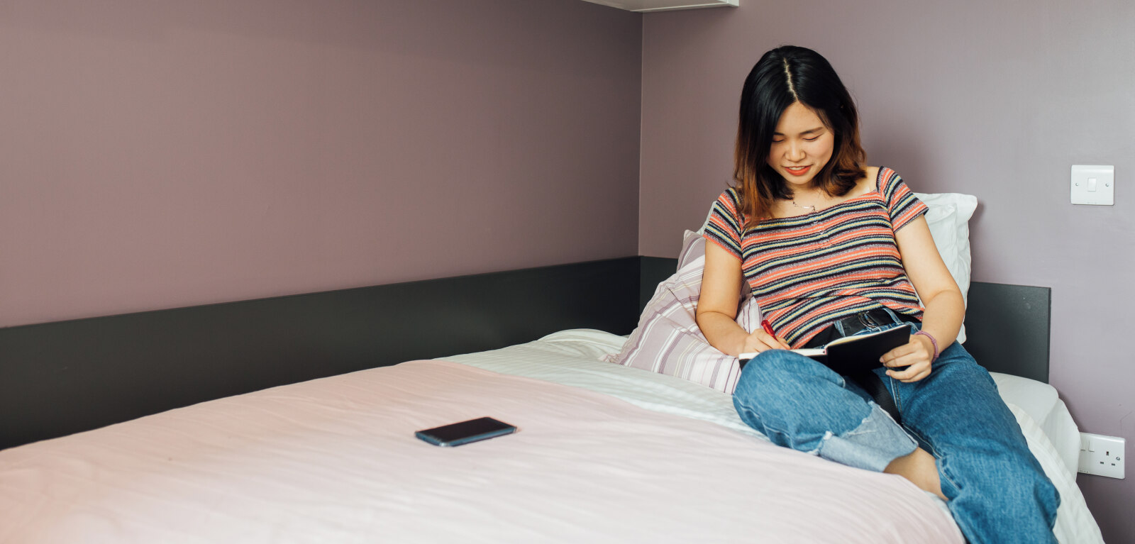 Student studying on top of bed in accommodation