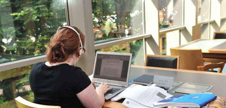 Student typing on laptop in the McClay Library