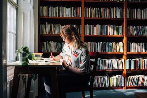 Student writing on desk in the Heaney Centre