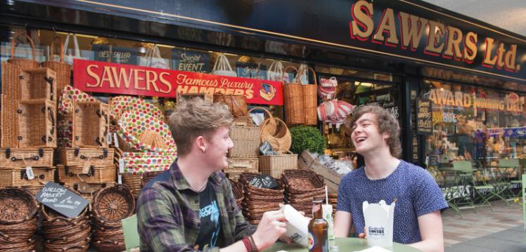 Two students eating outside Sawers