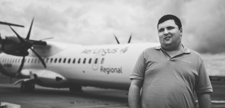 Black and white image of Thomas McClinton standing in front of Aer Lingus plane