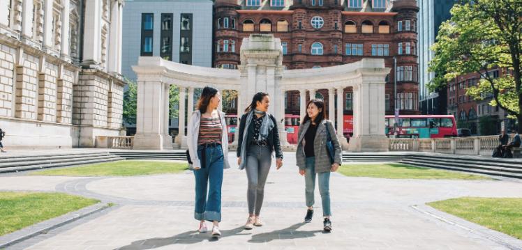 Three students walking through City Hall grounds