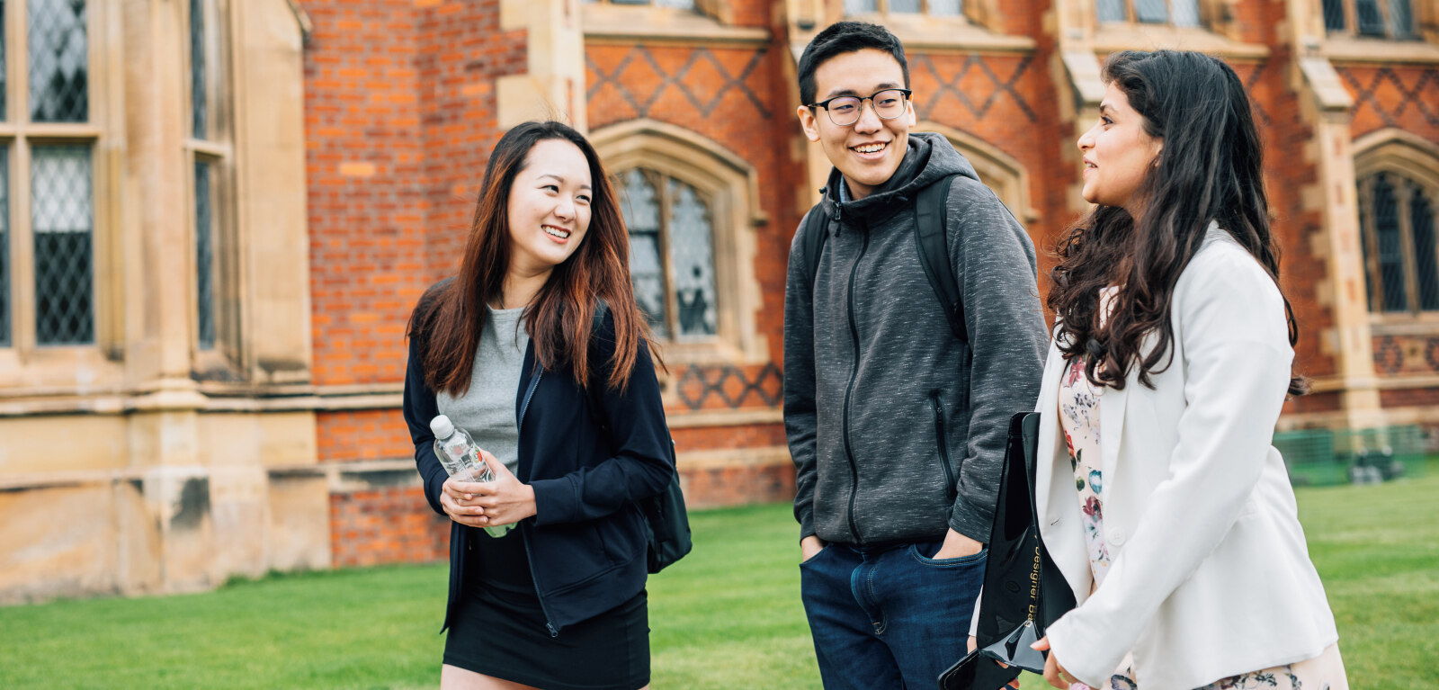 Three students walking past front of Lanyon