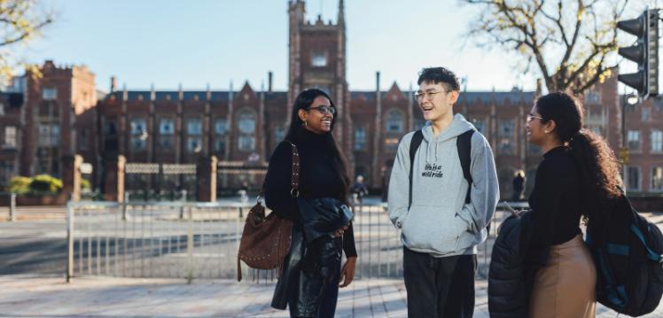 Three students standing outside One Elmwood across the road from the Lanyon