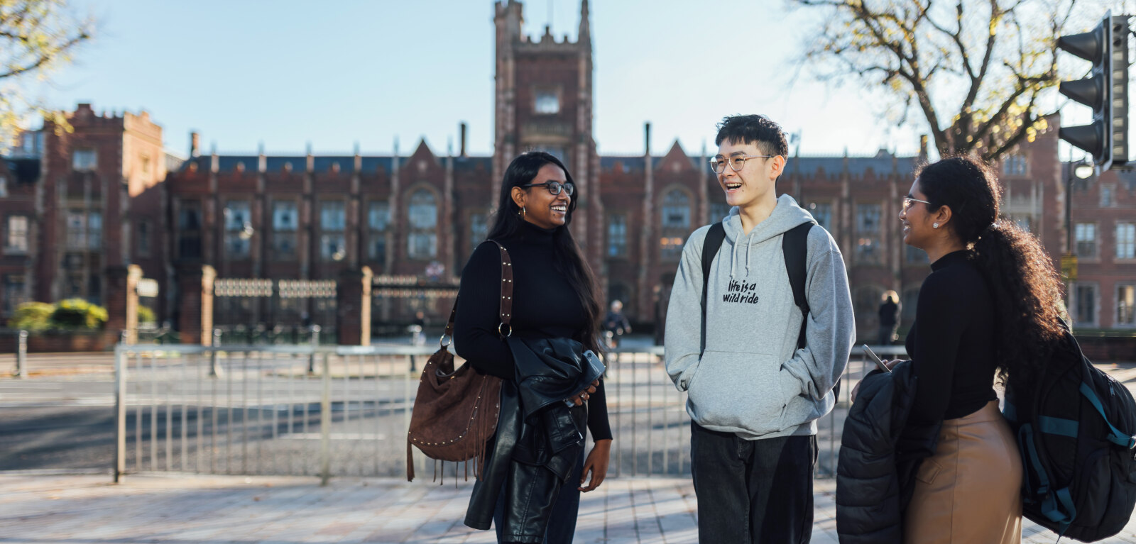 Three students standing outside One Elmwood across the road from the Lanyon