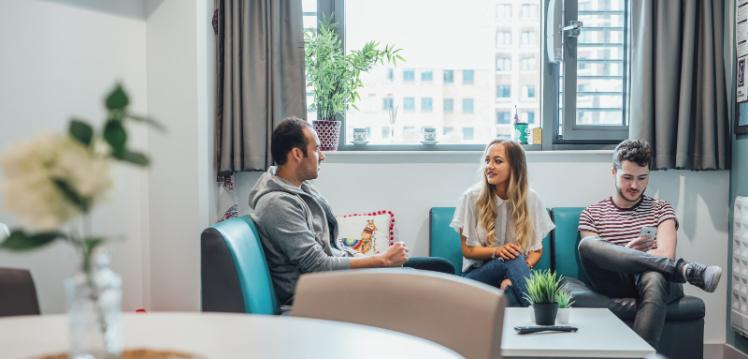 Three students sitting on sofa in accommodation