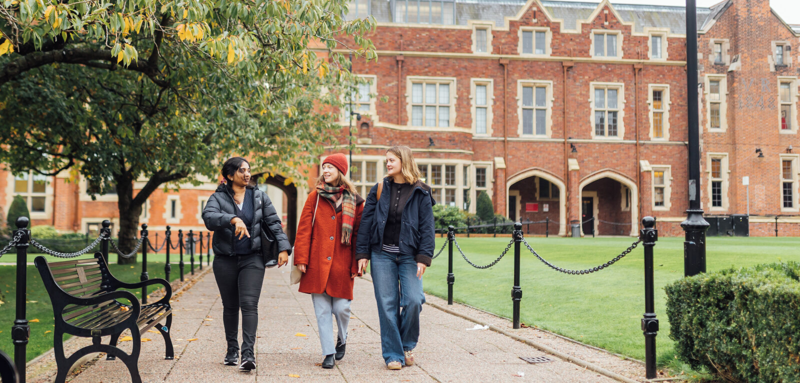 Three female students walk through the Quad