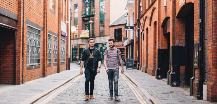 Two male students walking down cobblestoned street in Cathedral Quarter