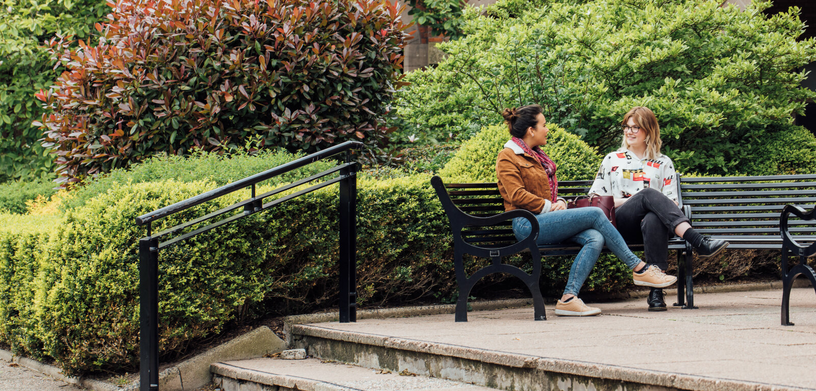 Two students sitting on a bench in the Quad