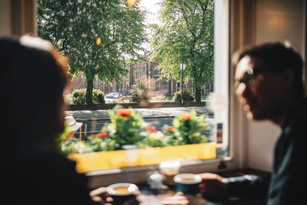 Two students having coffee in cafe in front of the Lanyon