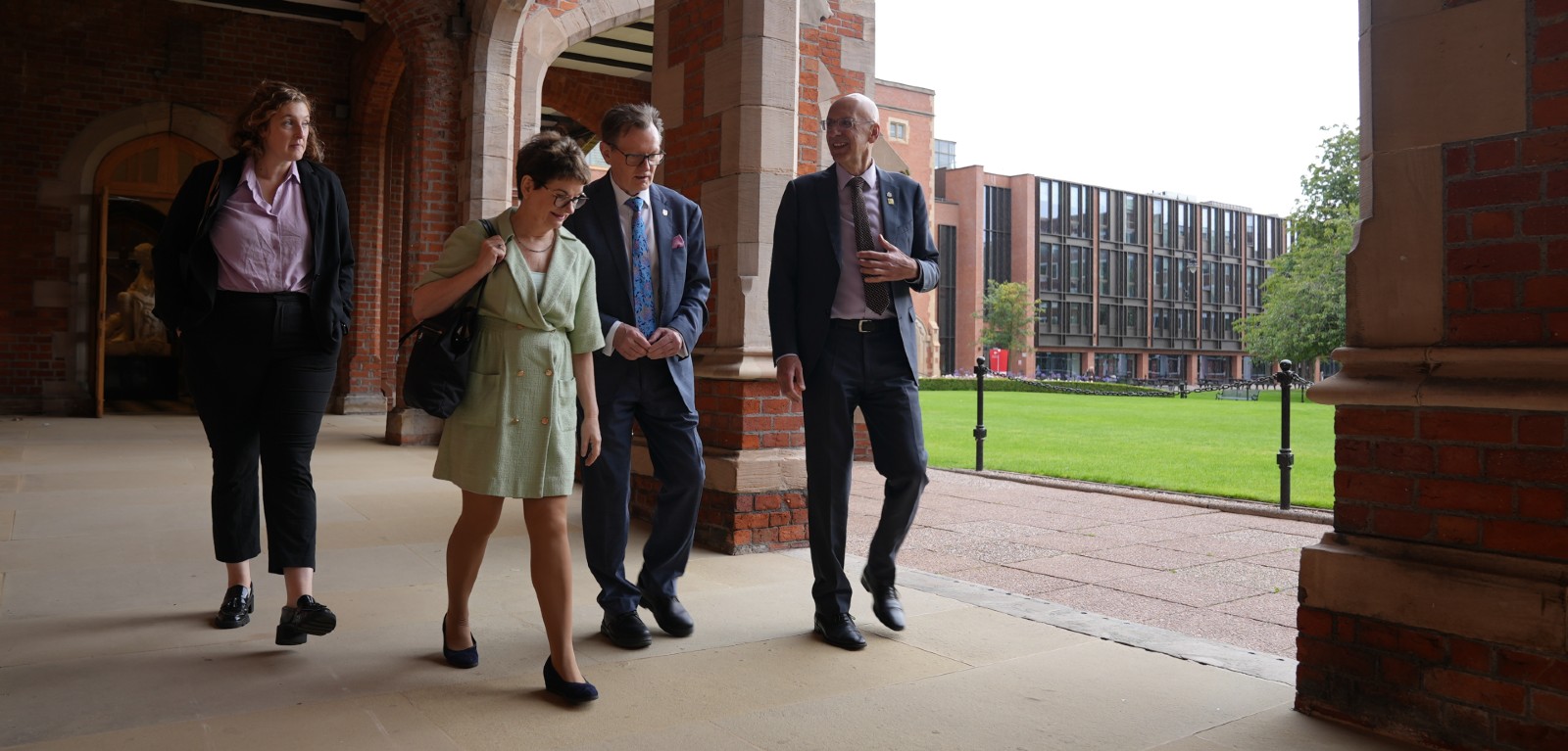 Two women and two men pictured in conversation as they walk across a university campus