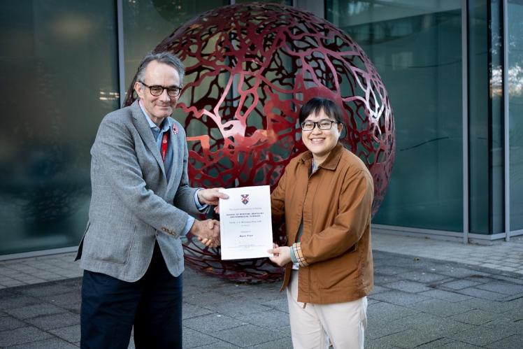 Professor Alan Smyth, Dean and Head of the School of Medicine, Dentistry and Biomedical Sciences, presents the 2025 JD Williamson Prize to Ngan Tran