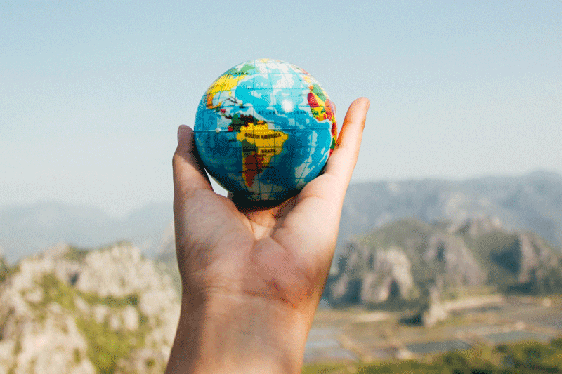A small globe held in front of canyon