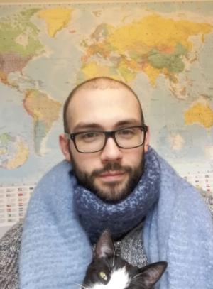 PhD student profile photo male student sitting front of a map of the world with a black and white cat on his lap