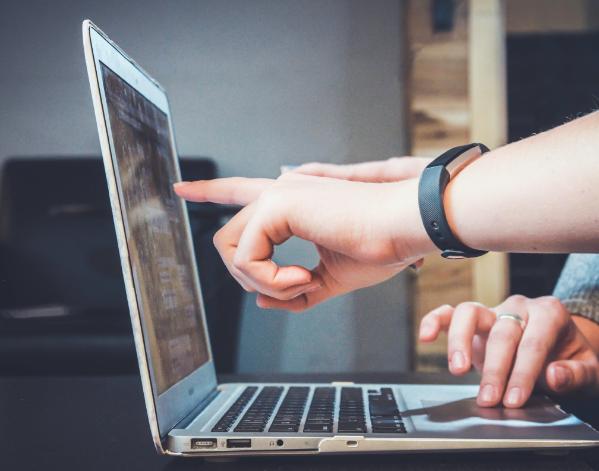 A person pointing at a laptop screen