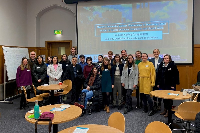 21 men and women in a row in front of a whiteboard displaying the title Framing Ageing Symposium