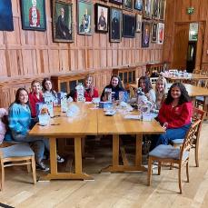 A group of smiling students with cuddly toys sitting around a table