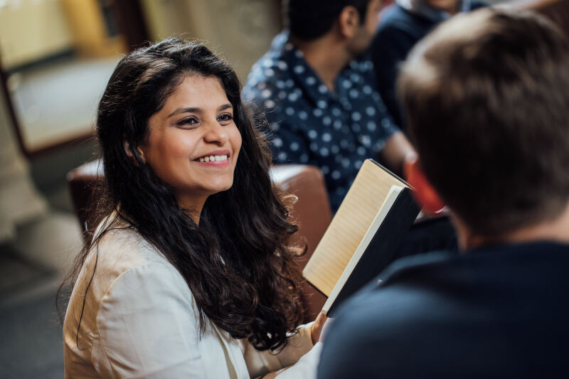 Student smiling in the common seating space in the Graduate School