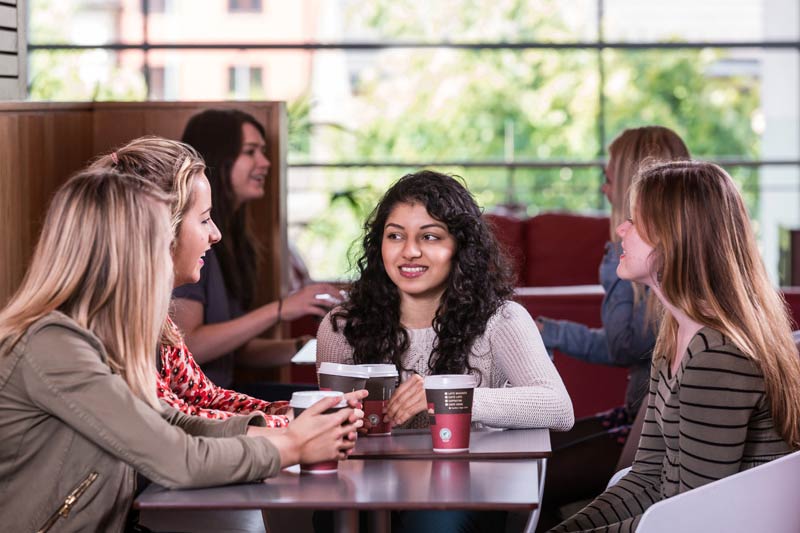 group of students drinking coffee in the treehouse area of Elms Village